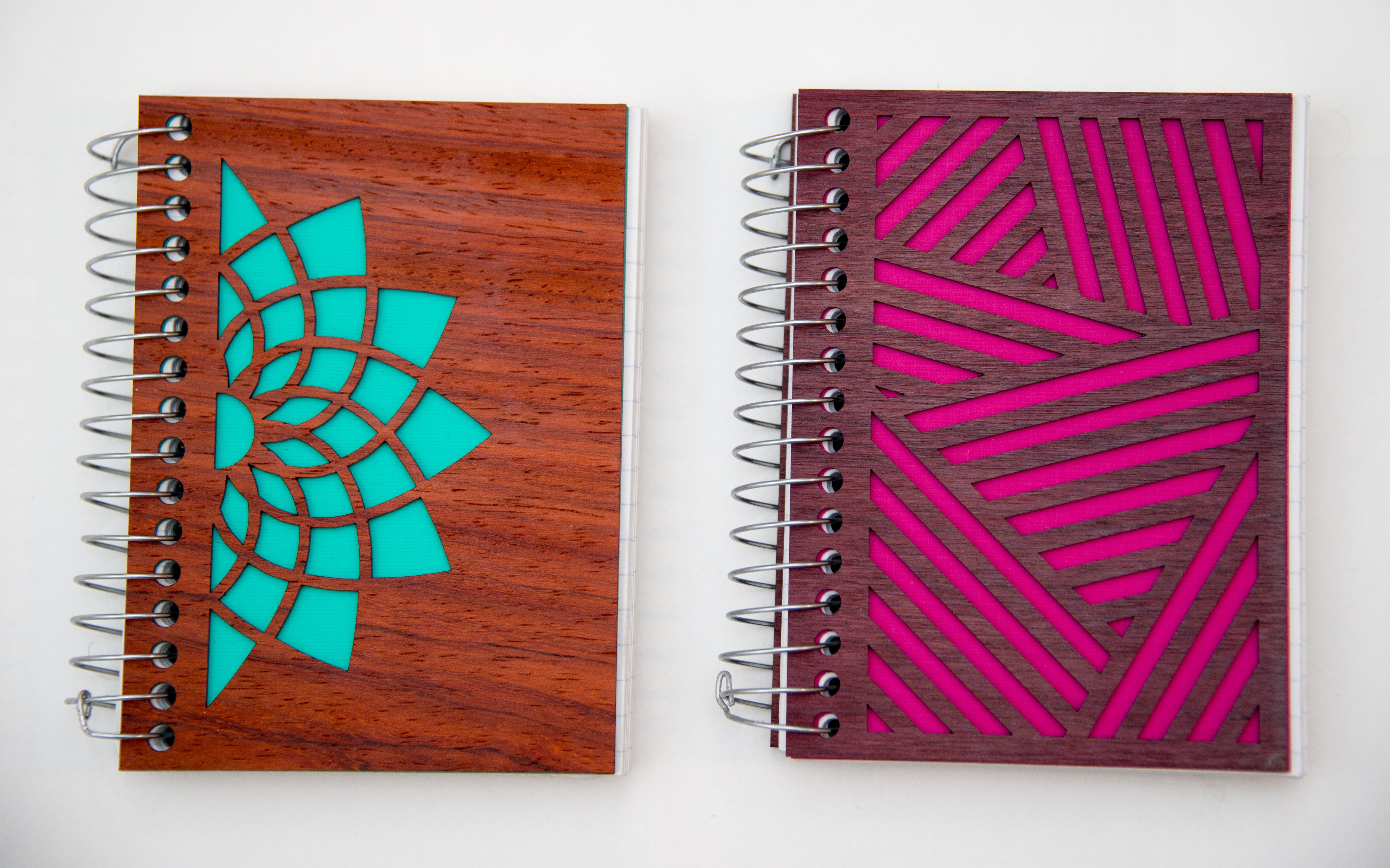 Two laser cut notebook covers with colored paper sshowing through